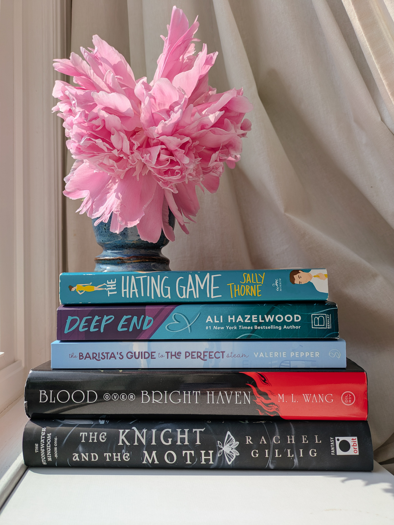 Stack of books, with a vase and peonies on top